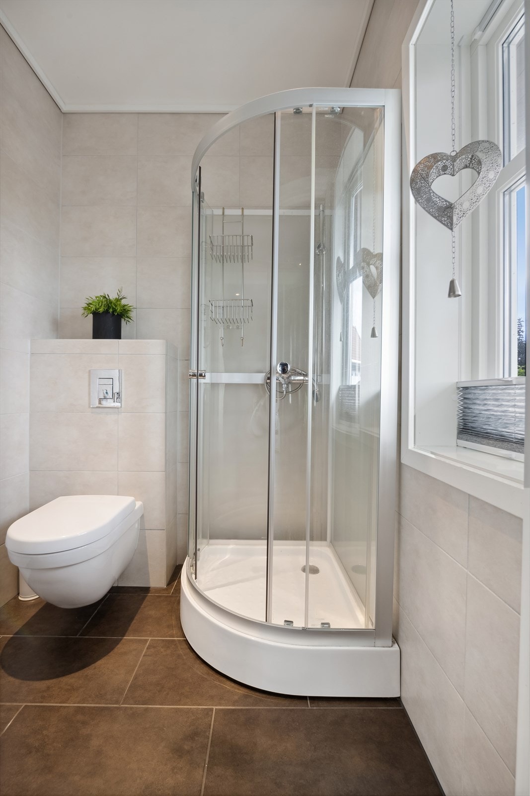 Bad i 1. etasje er helfliset og innredet med dusjkabinett, toalett og vask. Badet har ventilasjon via vinduet. Galleribilde