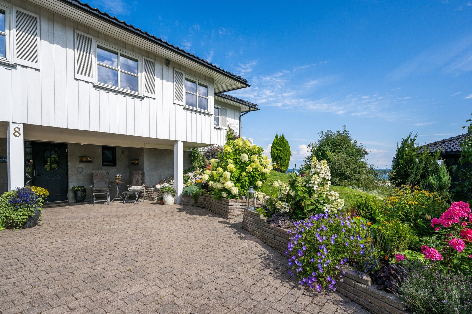 Stor og steinsatt gårdsplass og en frodig og flott hagetomt Galleribilde