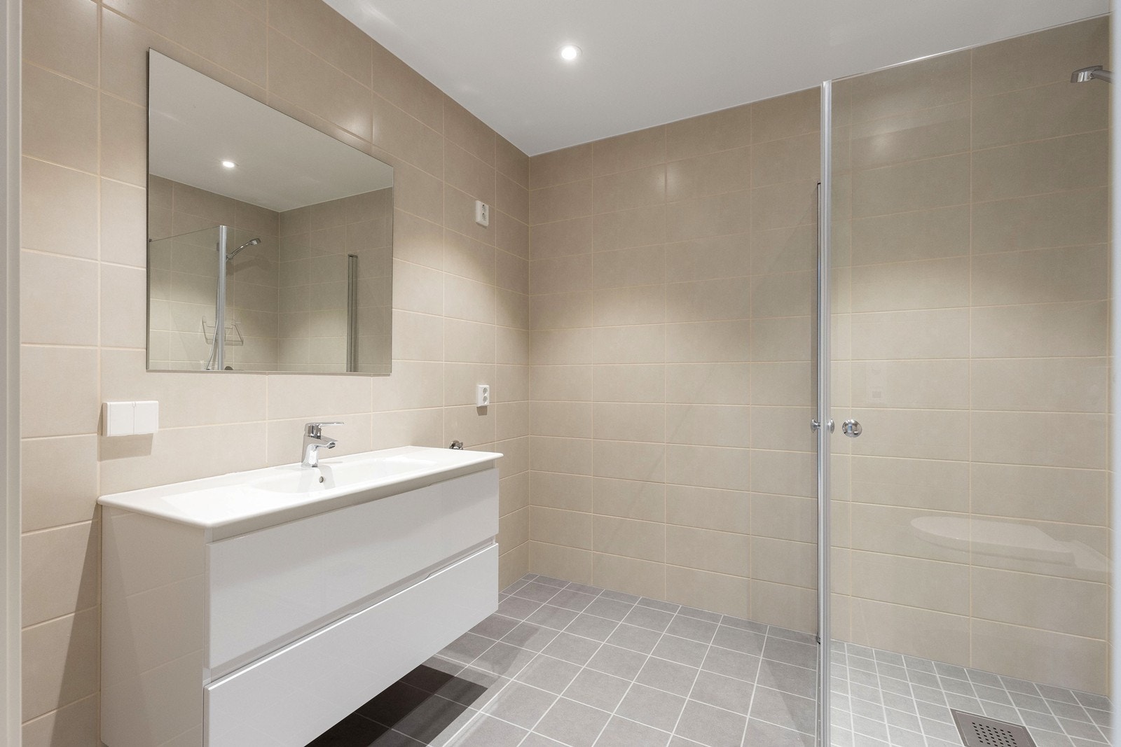 Badet inneholder moderne innredning med vask og speil, vegghengt toalett og dusjnisje. Galleribilde