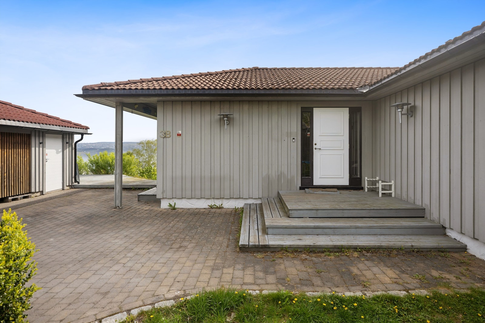 Gårdsplass med belegningssten samt vestvendt hage. Galleribilde