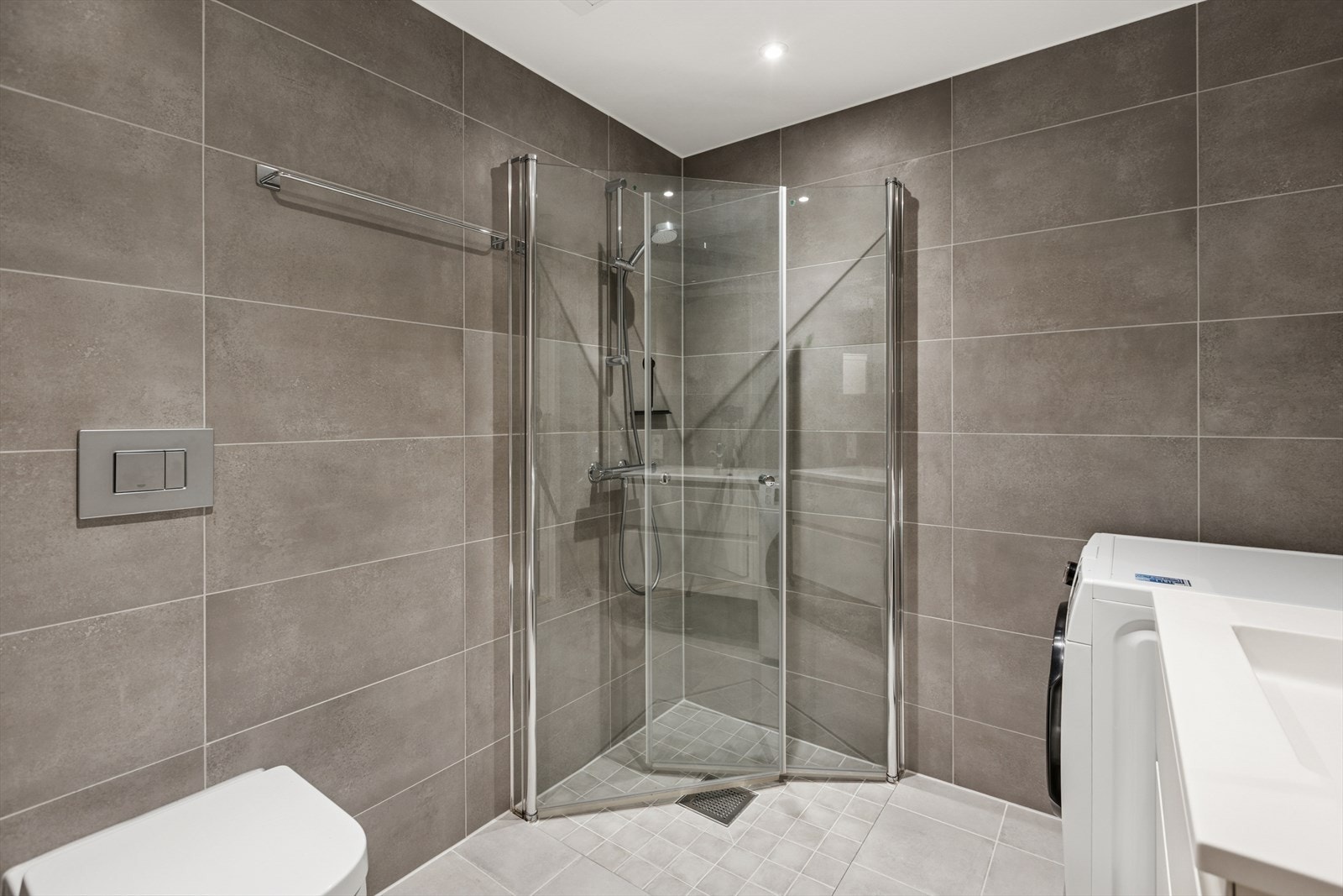 Badet er utstyrt med veggmontert toalett og dusjhjørne med svingbare skjermvegger. Galleribilde