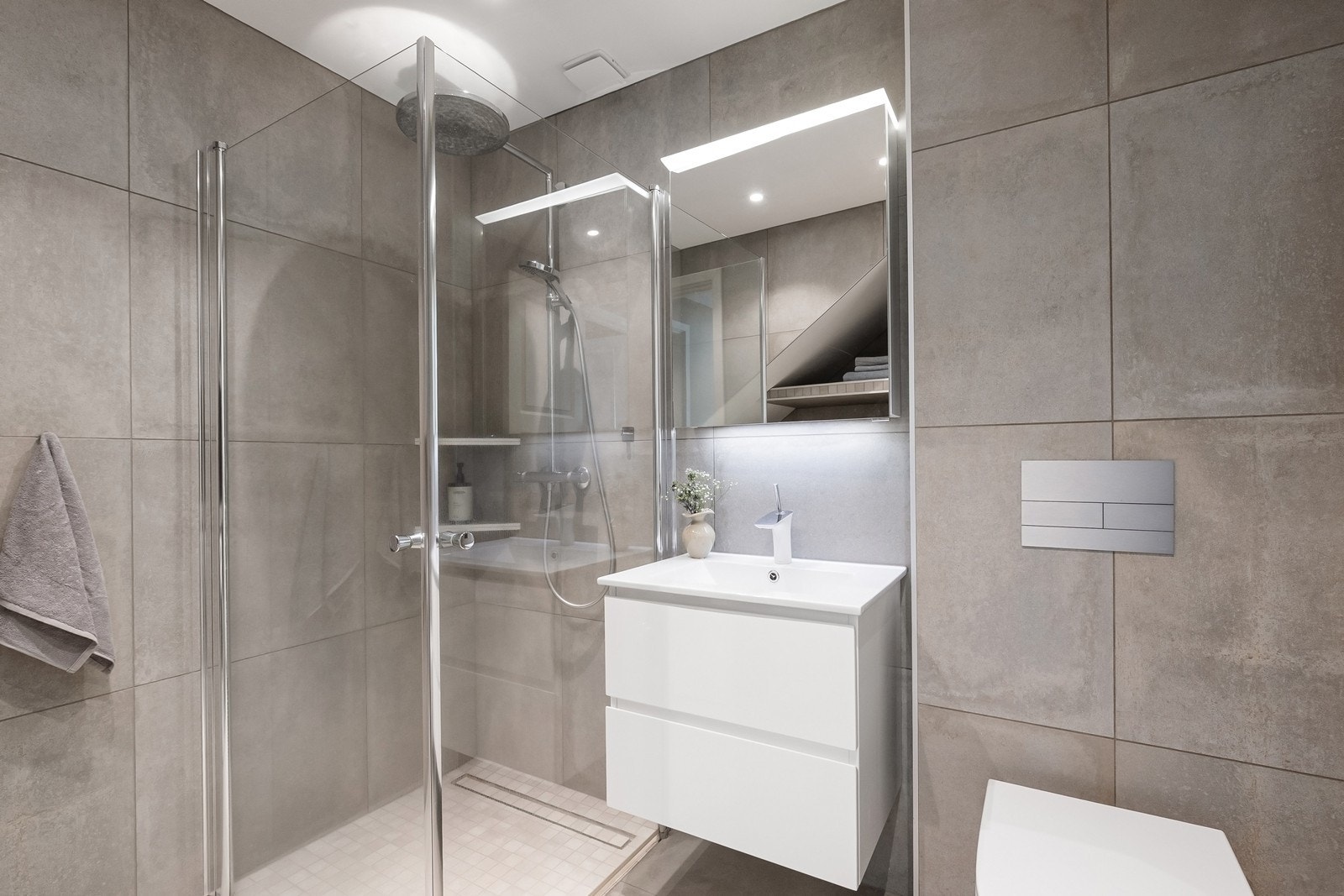 Kombinert bad og vaskerom i underetasje med tilsvarende moderne flisvalg og varme i gulv Galleribilde