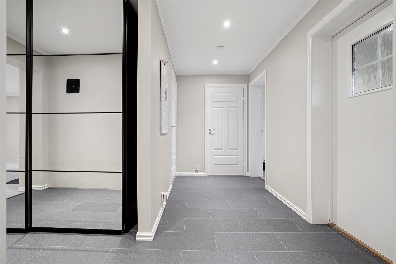 Romslig flislagt entre med skyvedørsgarderobe Galleribilde