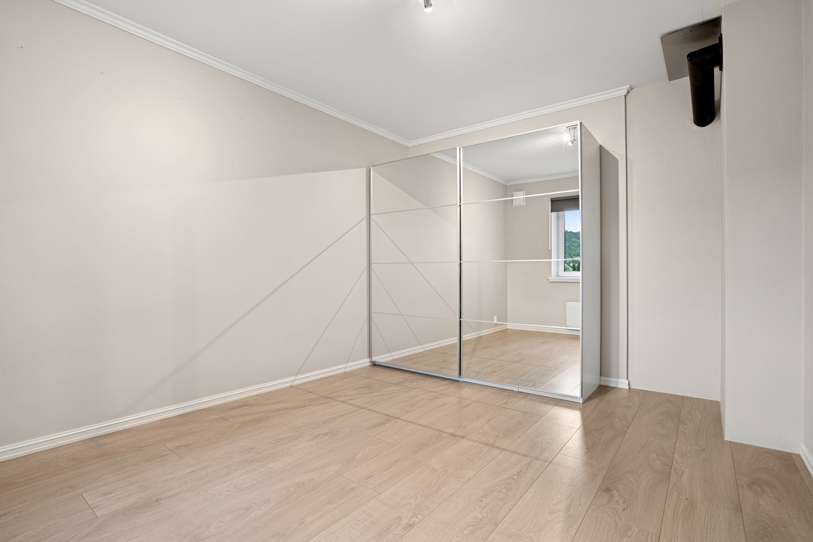 Lyst og innbydende rom med speilskyvedørsgarderobe og god plass til dobbeltseng, med moderne detaljer Galleribilde