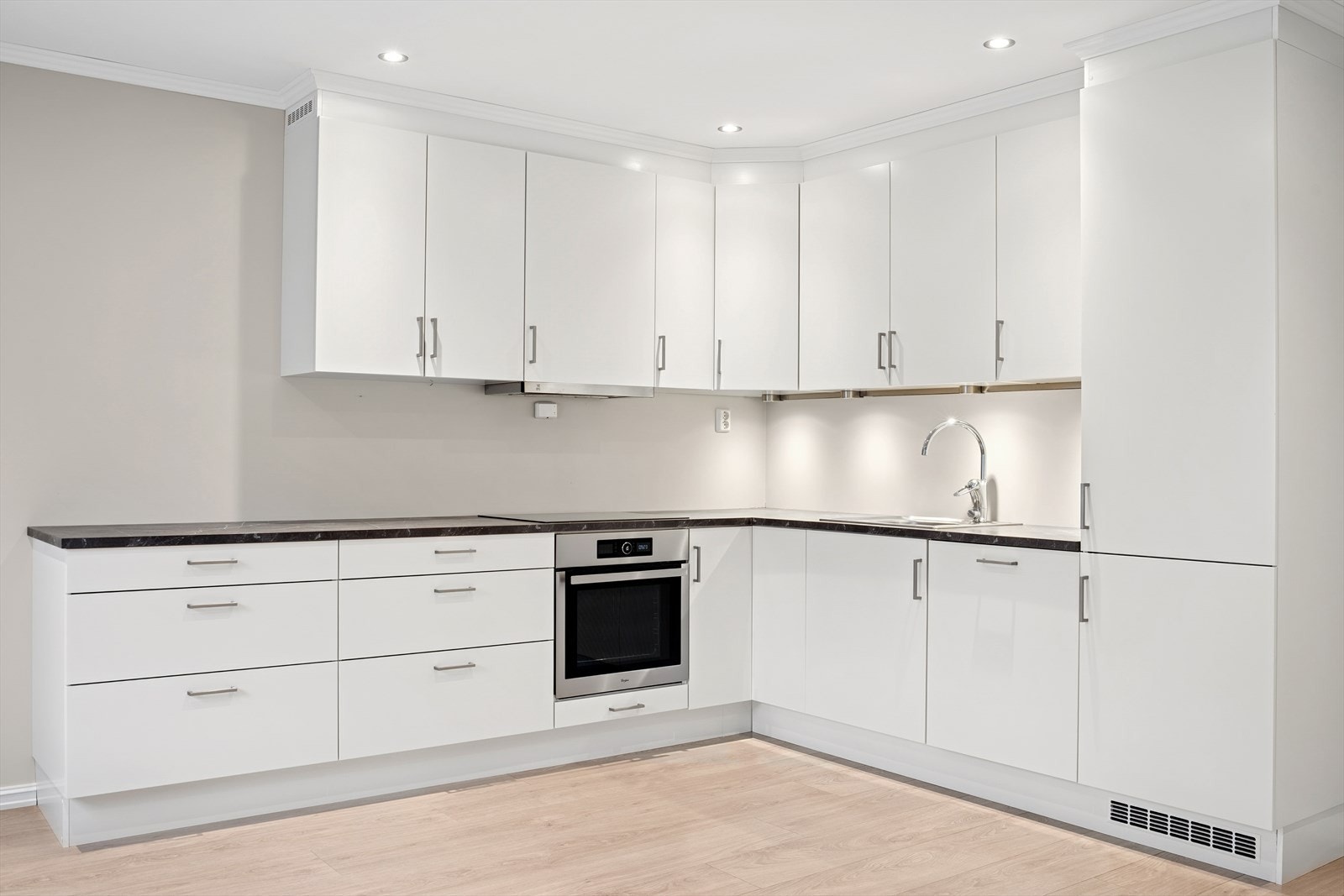 Kjøkkenet har en nøytral innredning med hvite glatte fronter og benkeplate i laminat. Galleribilde