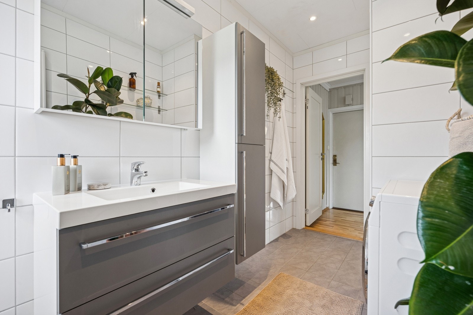 Baderommet fremstår moderne og delikat med lyse fliser på vegger, downlights i tak og et praktisk vindu. Galleribilde