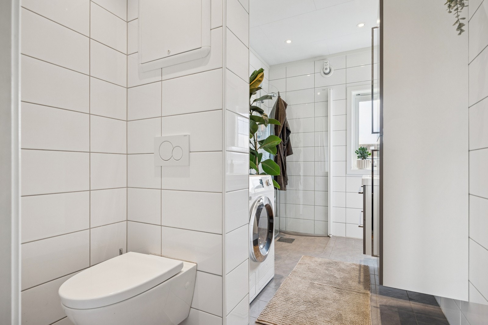 Baderommet er utstyrt med servant med underskap, seilskap med belysning, dusjhjørne med foldbare glassdører, vegghengt toalett, varmekabler i gulv og opplegg for vaskemaskin. Galleribilde