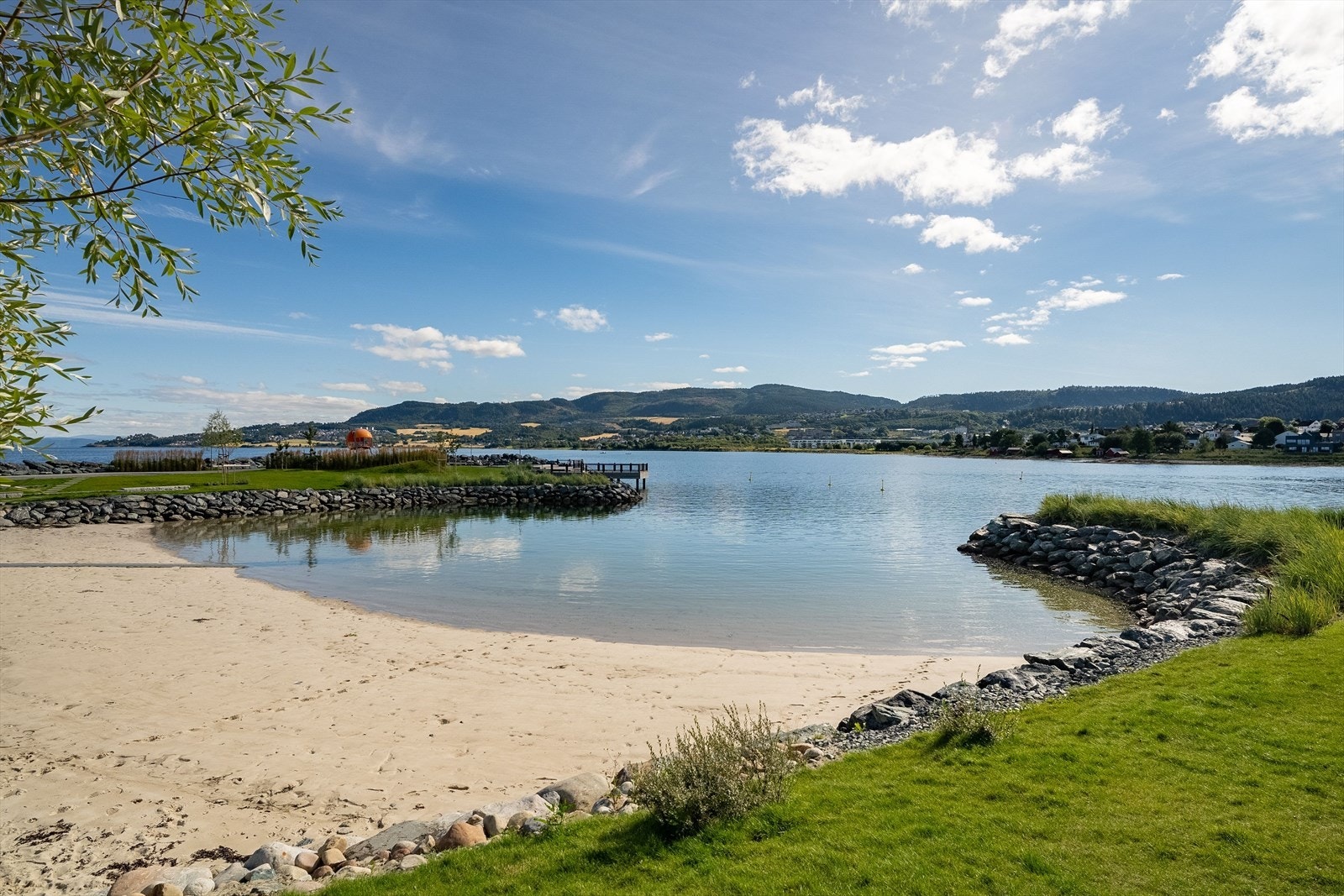 Omgivelsene er idylliske, med båtbrygge og sandstrand rett utenfor døren. Galleribilde