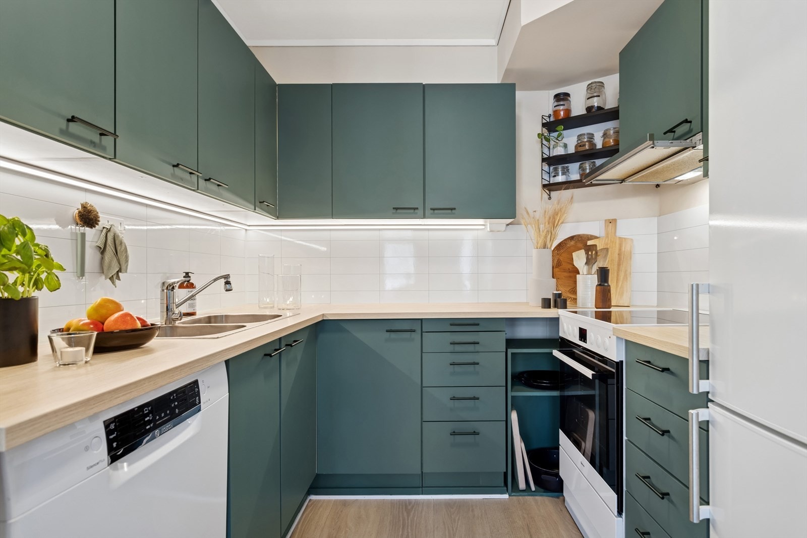 Kjøkkenet har en flott- og tidløs innredning bestående av folierte skrog med slette fronter og laminert benkeplate. Plater på vegg over benkeplate. Galleribilde
