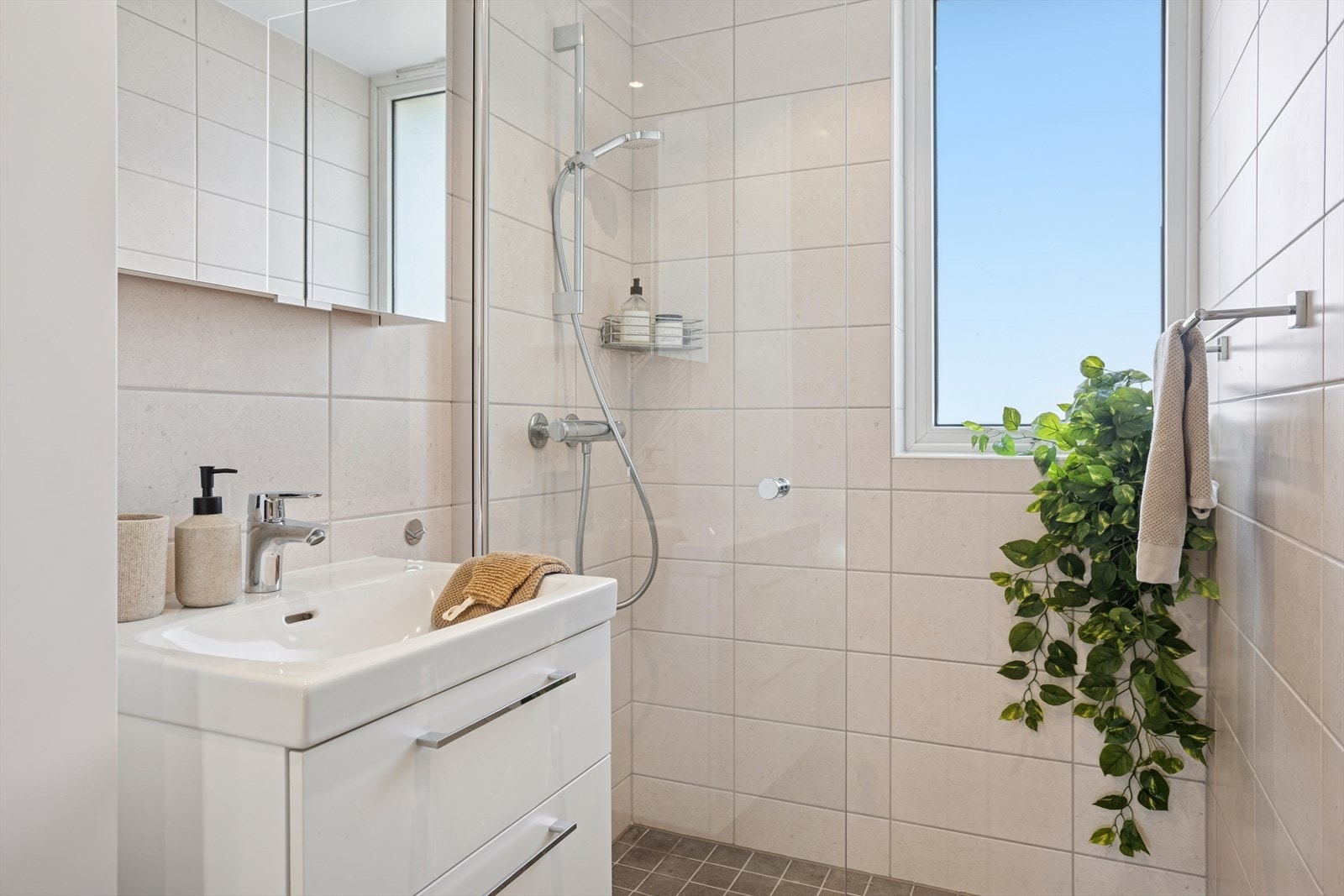 Badet er innredet med vegghengt toalett, dusj med glassnisje, servant med underskap, speil og integrert belysning. Galleribilde