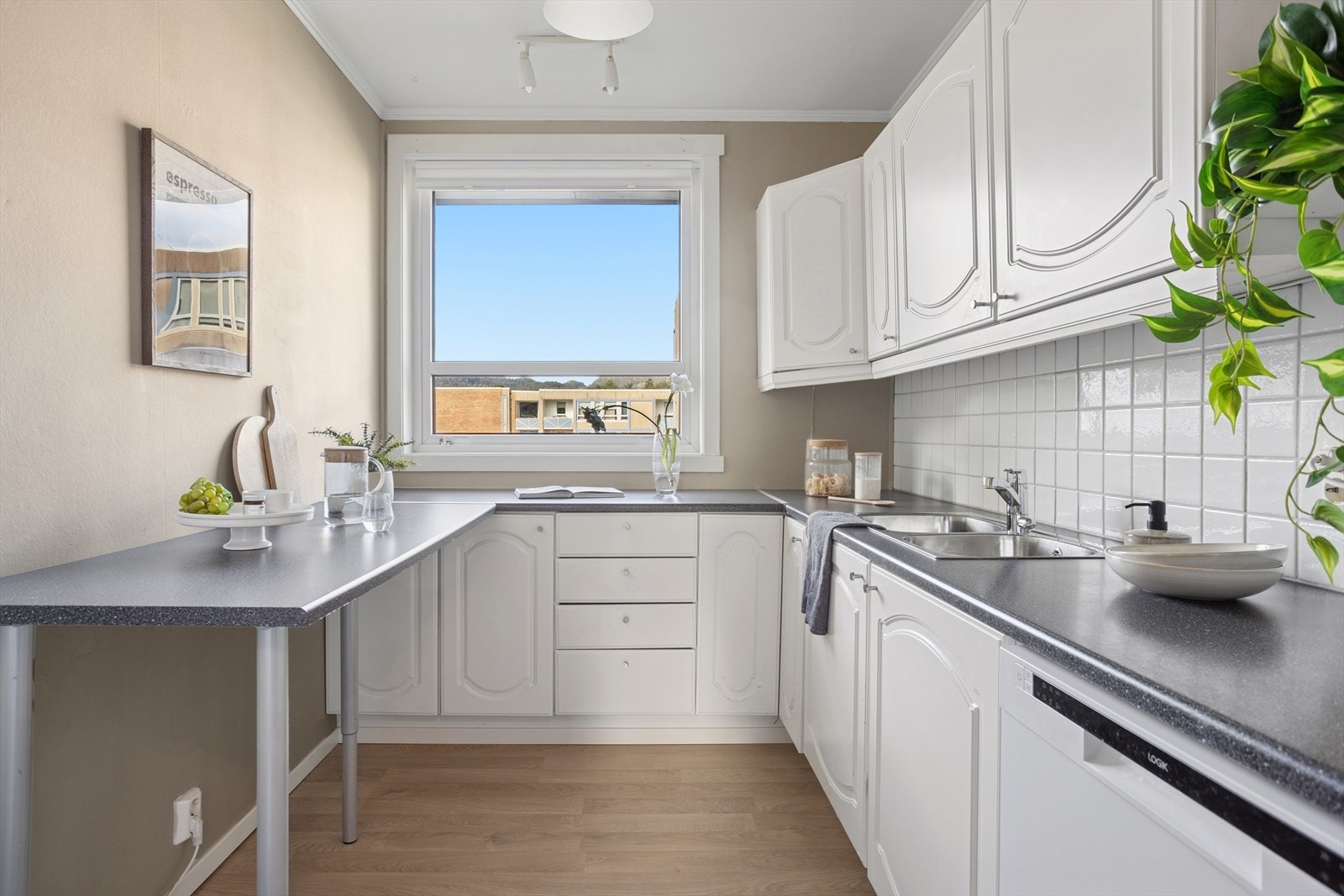 Kjøkkenet har innredning med profilerte fronter og laminert benkeplate med integrert vask i rustfritt stål. Galleribilde