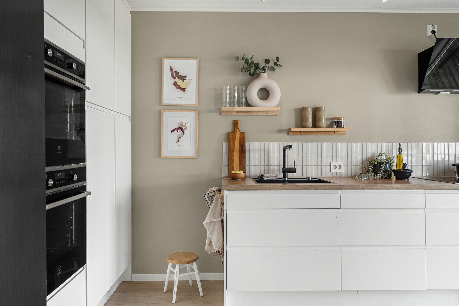 Stilren innredning med hvite glatte kjøkkenfronter med integrerte dørhåndtak. Galleribilde