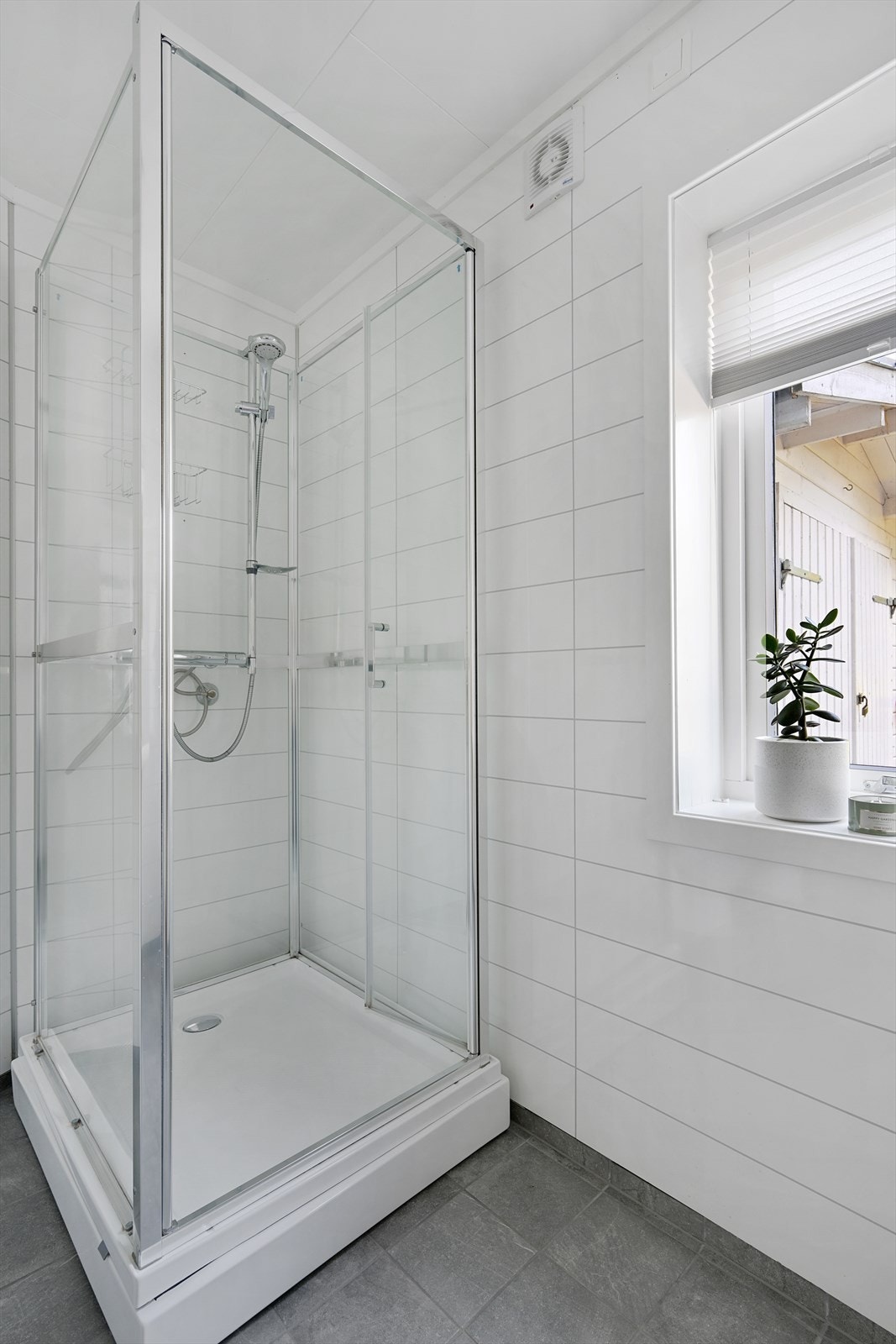 Badet har fliser på gulv og baderomsplater på veggene Galleribilde