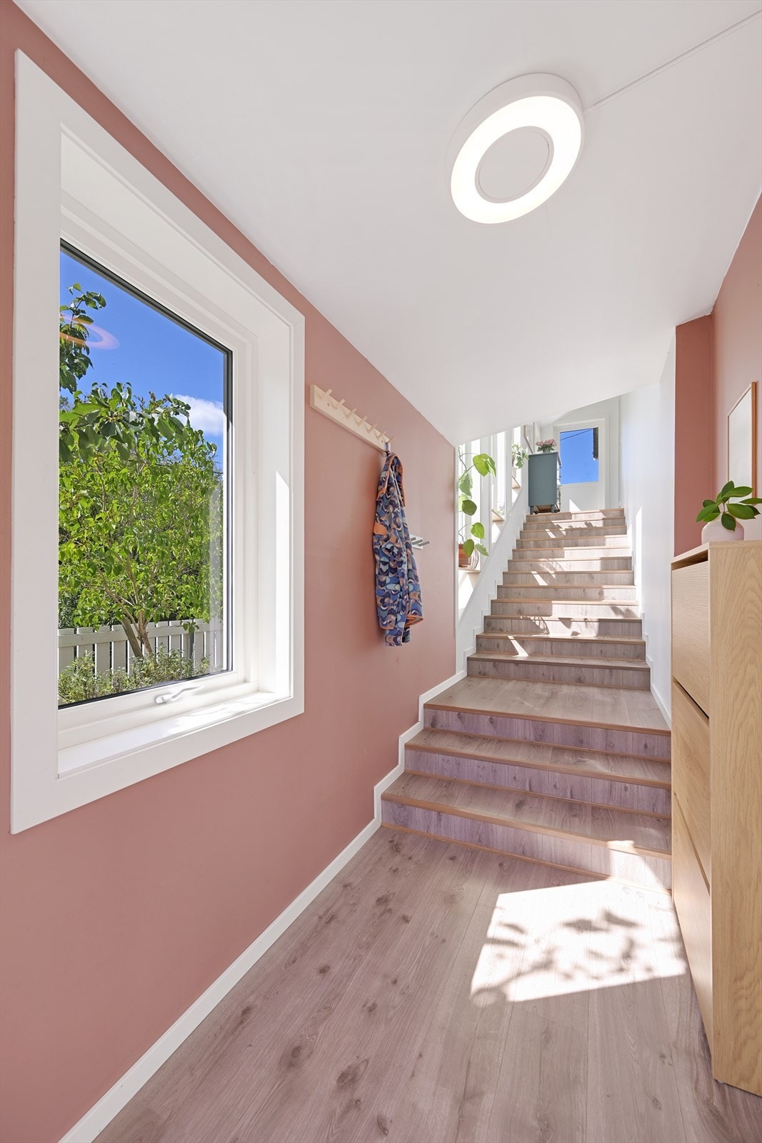 Et nydelig trapperom med store vindusflater mot vest, fører deg opp til hovedetasjen. I enden av trappen har du også en terrassedør ut til skiferterrassen og uteområdet på nordsiden av huset Galleribilde