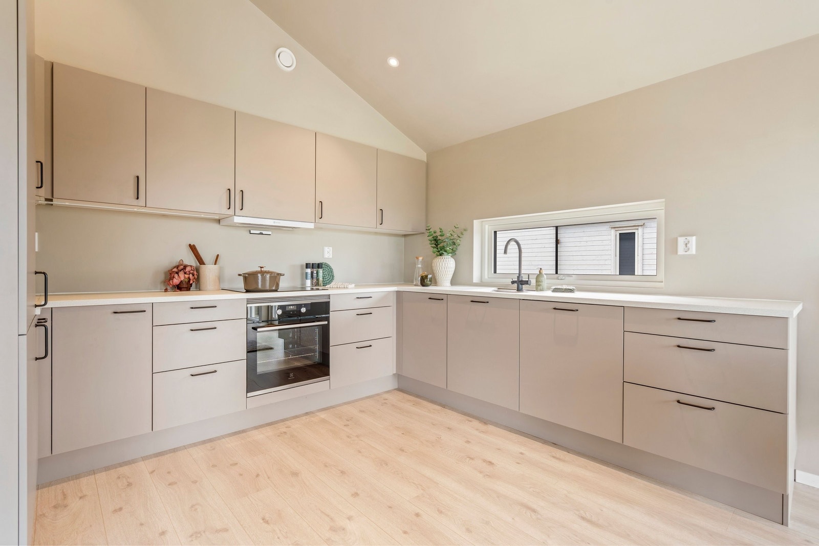 Kjøkkenet har stilrene fronter i nøytral fargetone, integrerte hvitevarer og rikelig med skap- og benkeplass. Galleribilde