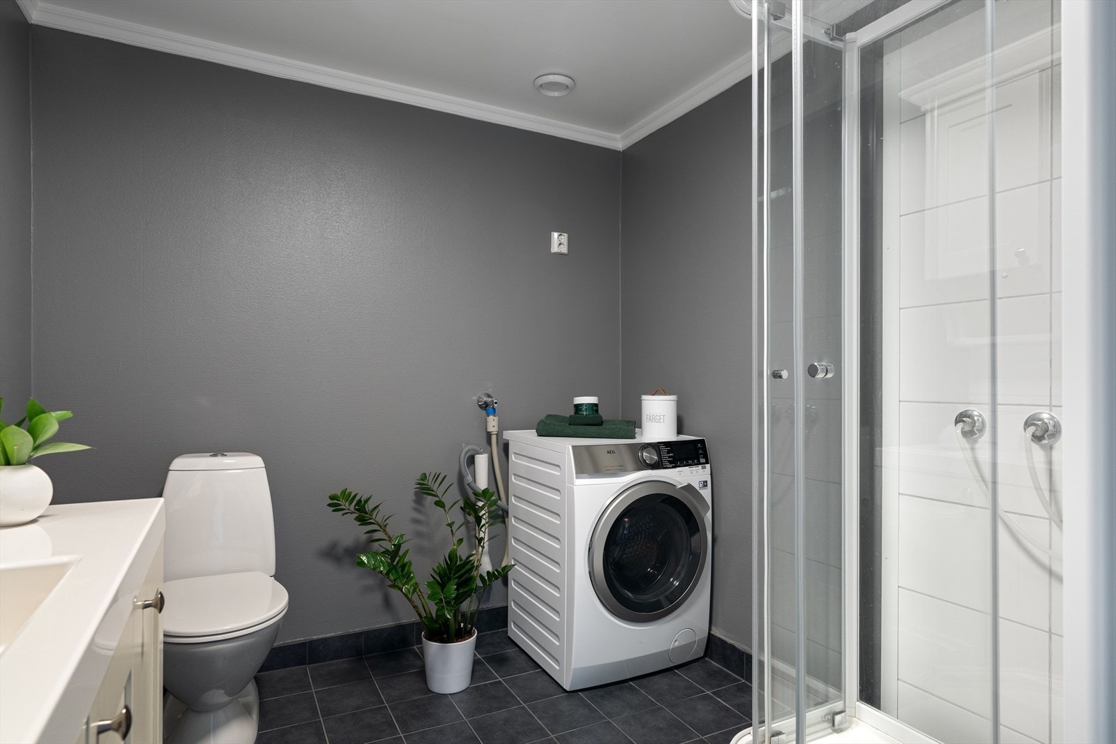 Badet er innredet med dusjkabinett, vegghengt tørkestativ og opplegg for vaskemaskin. Galleribilde