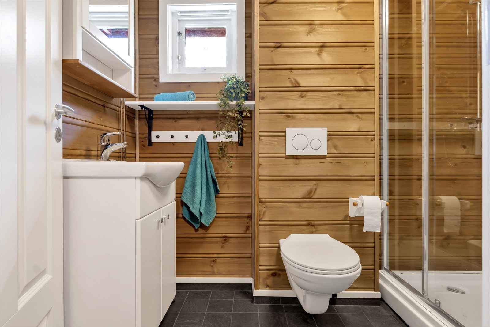 Hyttens bad er fra 2017, med fliser på gulvet og panel på veggene. Galleribilde