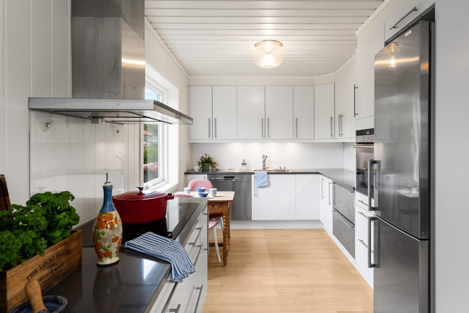 Kjøkkenet er praktisk utformet, med hvite, glatte fronter og en benkeplate i stein som tåler daglig bruk. Galleribilde