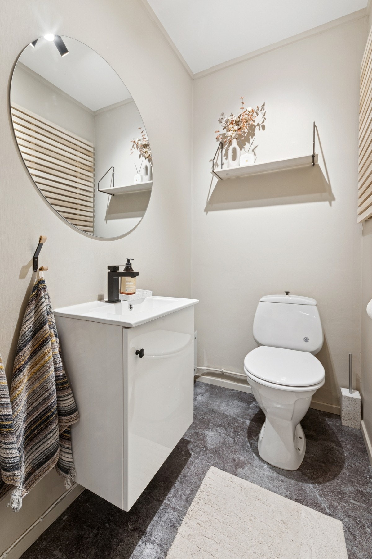 Praktisk toalettrom vegg-i-vegg med badet, med enkel innredning med servant, speil og underskap. Galleribilde