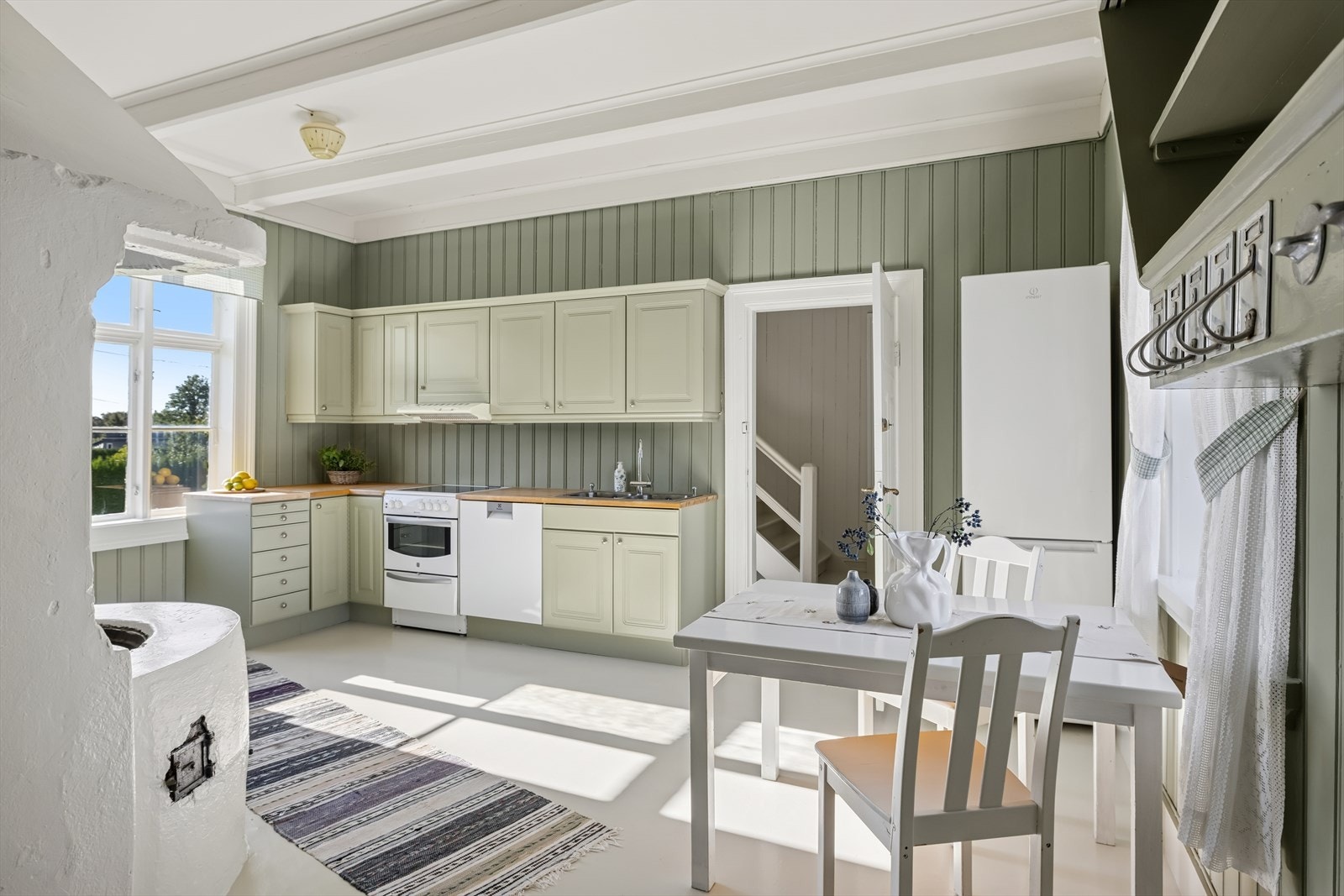 Hyggelig kjøkken/spisestue med innredning med malte speilfronter og benkeplate i tre. Galleribilde