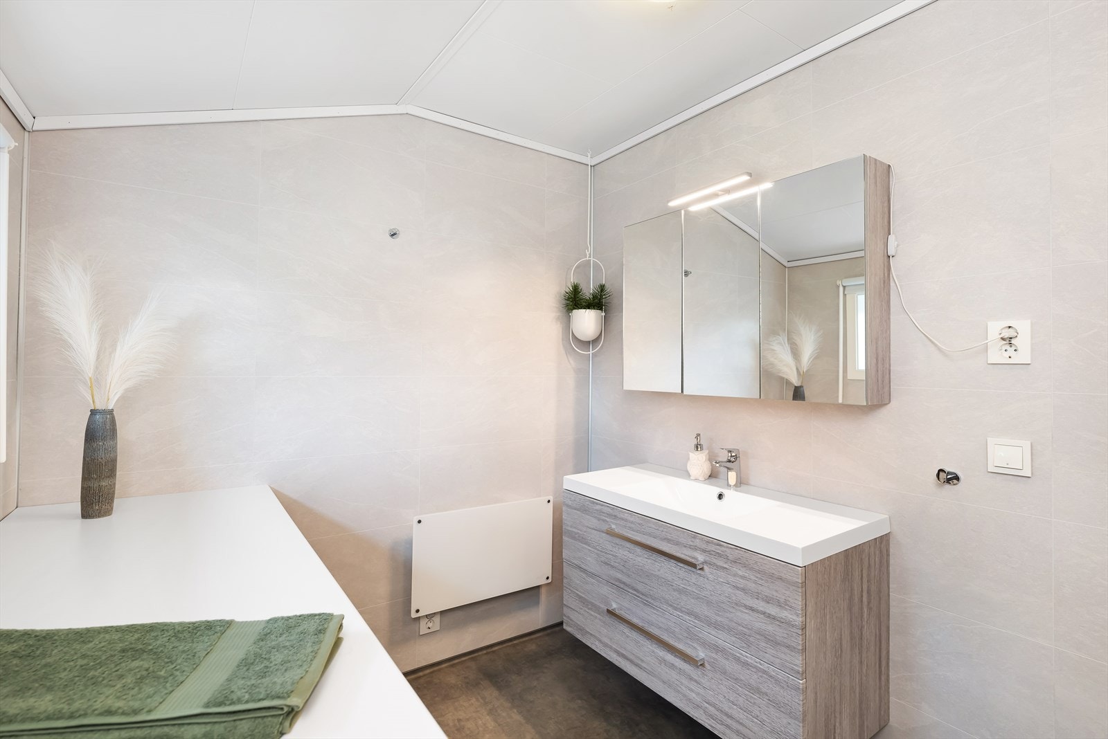 Badet er innredet med toalett, benkeskap med servant, dusjkabinett og opplegg for vaskemaskin. Galleribilde