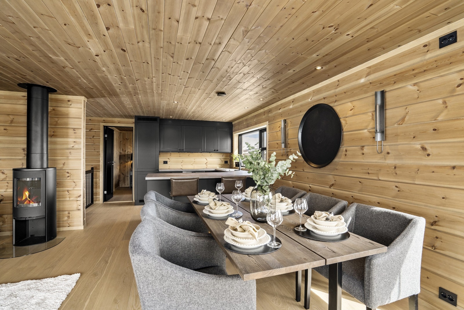 Fra spiseplass mot kjøkken. Peisovn. Soverom og bad i enden. Galleribilde