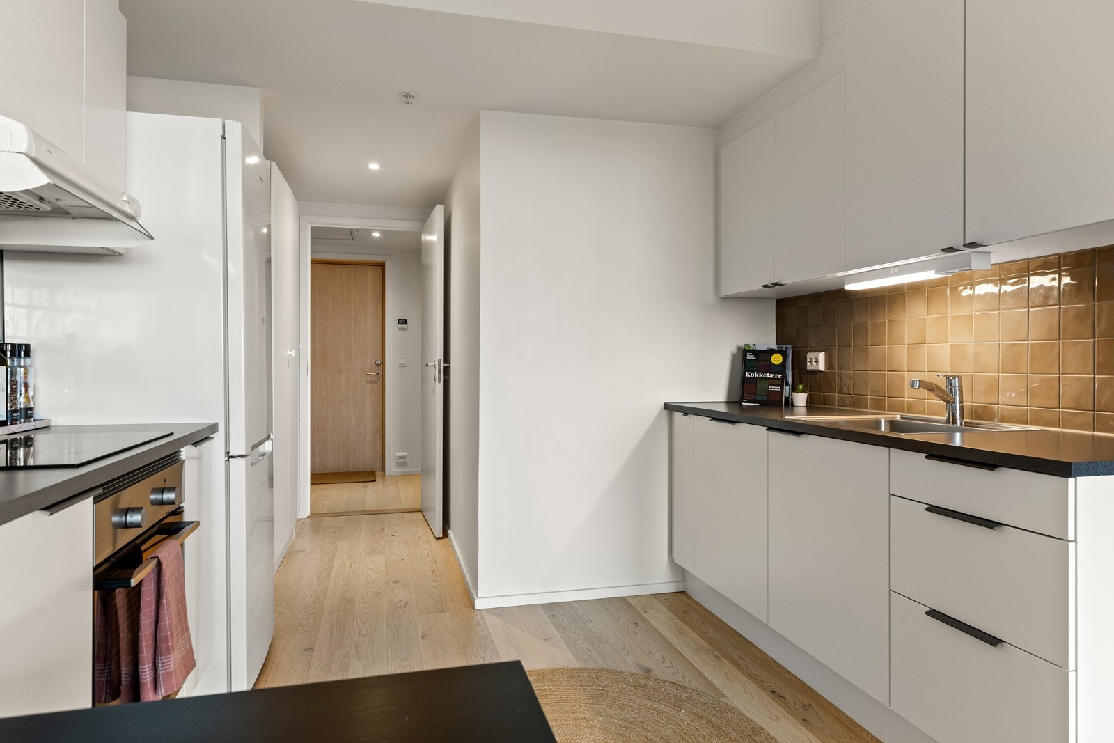 Stilrent kjøkken med hvite, glatte fronter og benkeplate i laminat. Galleribilde