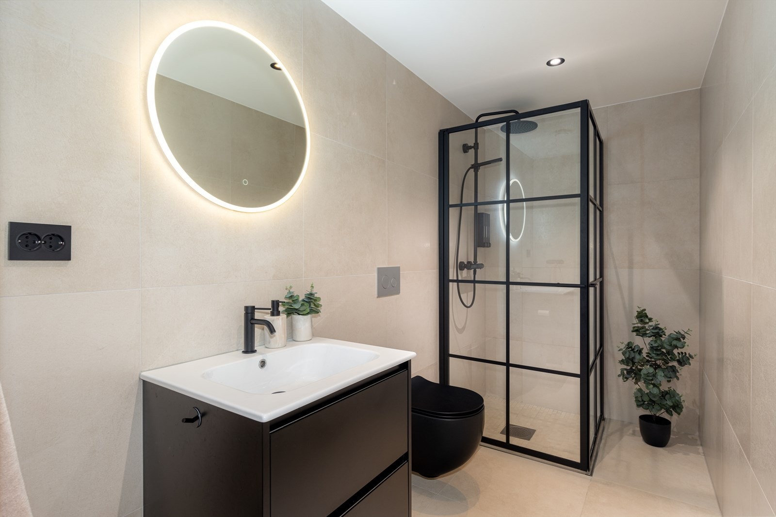 Badet i 1. etasje er helfliset med vannbåren gulvvarme, og gir et eksklusivt og rolig helhetsinntrykk. Det runde speilet på veggen gir et stilrent uttrykk kombinert med varm og behagelig belysning. Galleribilde