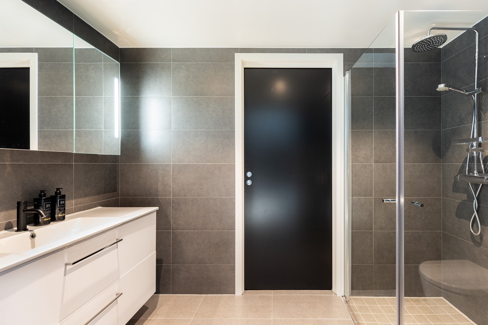 Badet i 2. etasje er helfliset med varmekabler i gulvet. Her er en baderomsinnredning i høyglans hvit utførelse med dype skuffer. Galleribilde