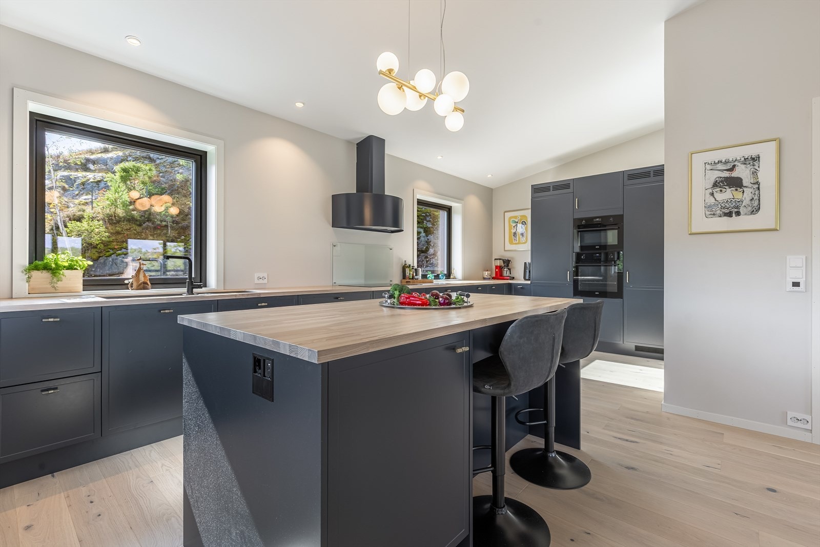 Strai Lysefjord kjøkken med stor kjøkkenøy, benkeplater i heltre Ask (hvitpigmentert), RørosHetta kjøkken ventilator og AEG hvitevarer. Galleribilde