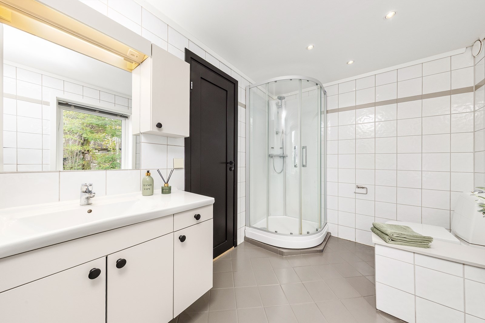 Lyst flislagt bad utstyrt med dusjkabinett og gulvstående toalett. Galleribilde