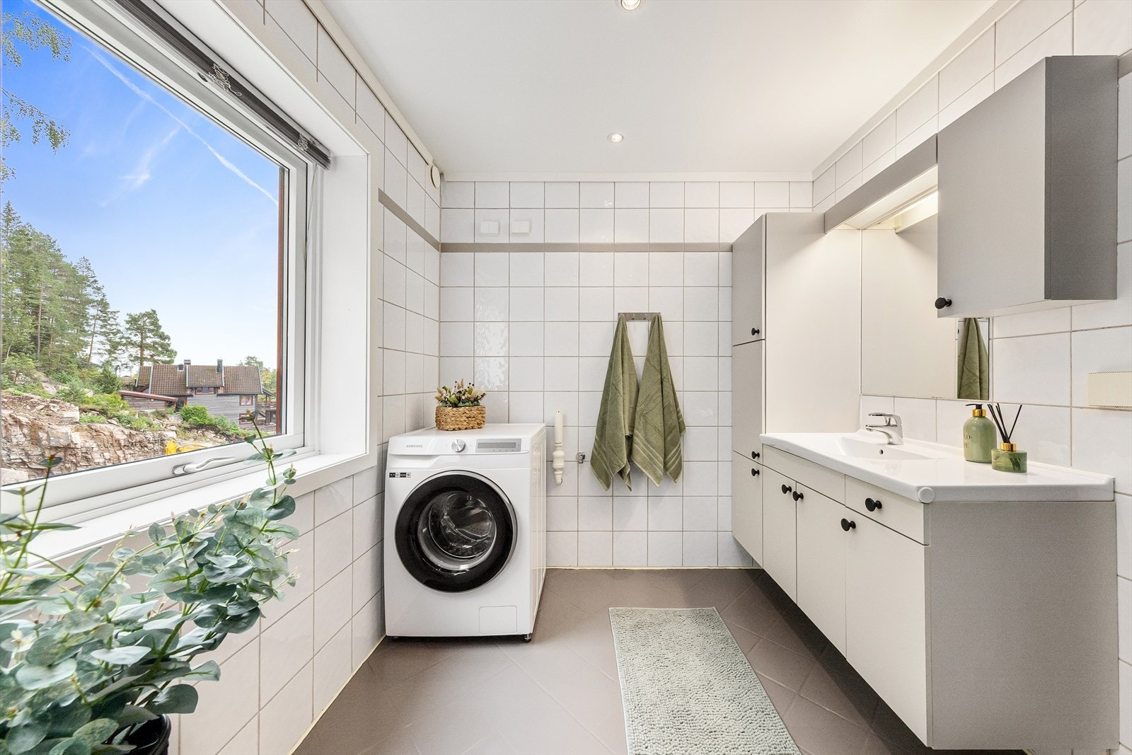 Her er det også opplegg for vaskemaskin. Lys og romslig baderomsinnredning med mye oppbevaringsplass. Galleribilde