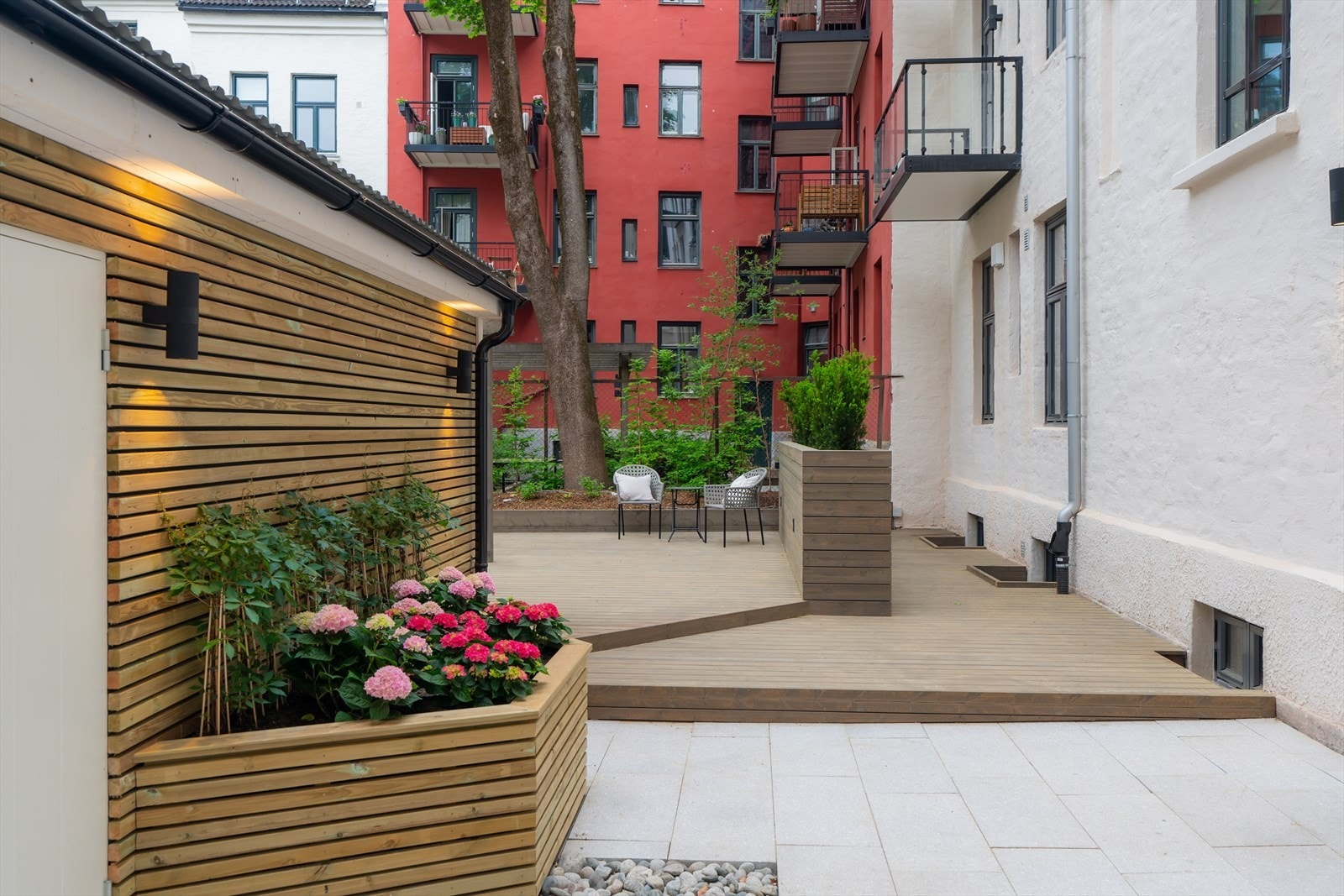 Hyggelig fellesarealer i bakgård med terrasse, beplantning, sykkelparkering og avfallshåndtering. Galleribilde