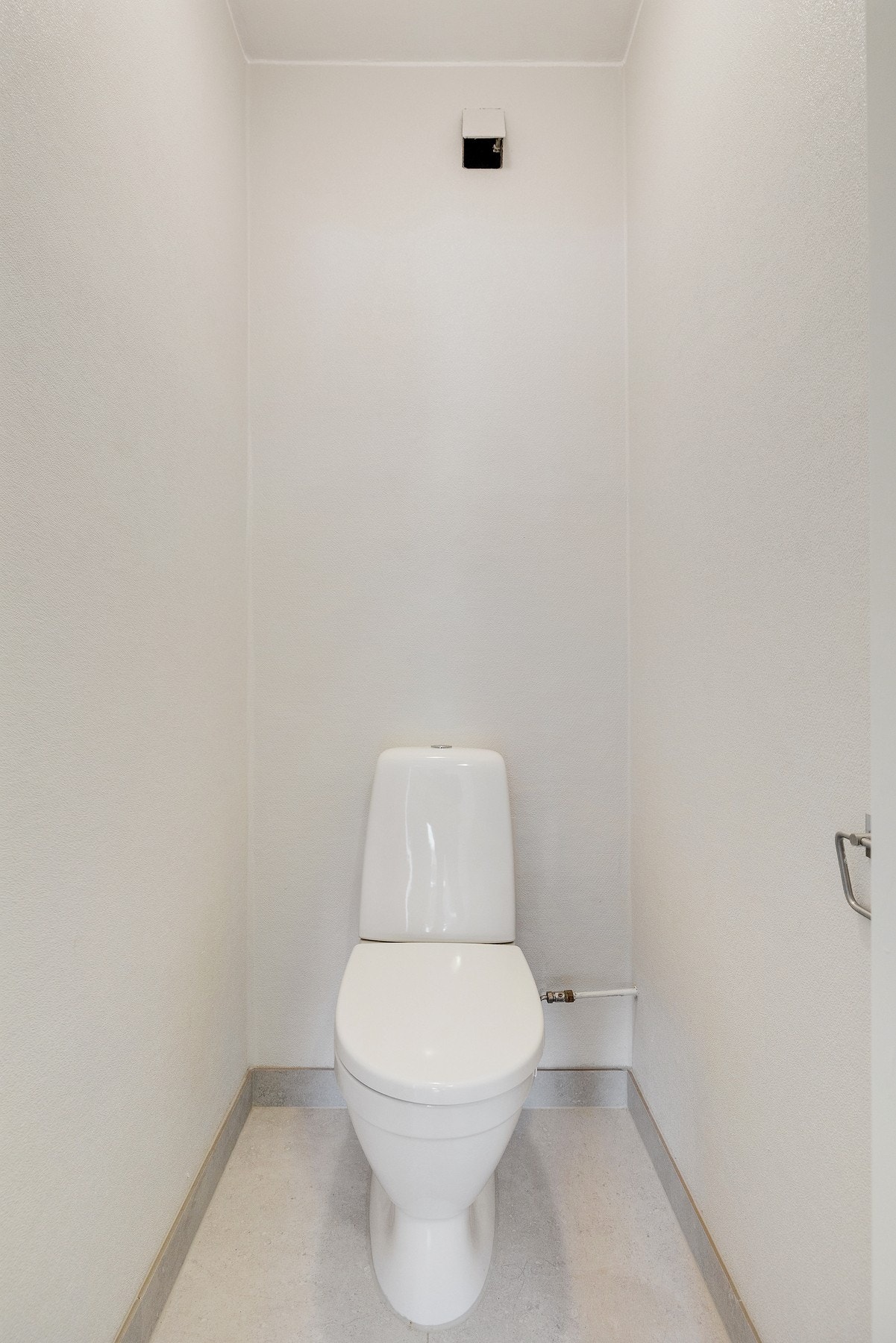 Toalettrom med flislagt gulv og malte vegger. Gulvstående toalett. Galleribilde