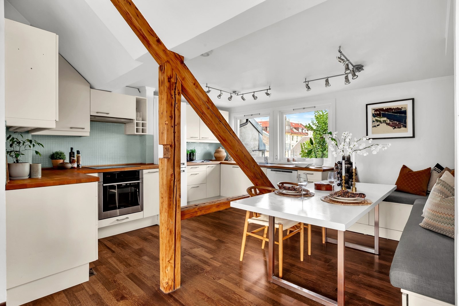 Stilrent kjøkken med innredning bestående av over- og underskap med glatte fronter, benkeplate i eik, og glassmosaikkfliser på vegg over benk. Galleribilde