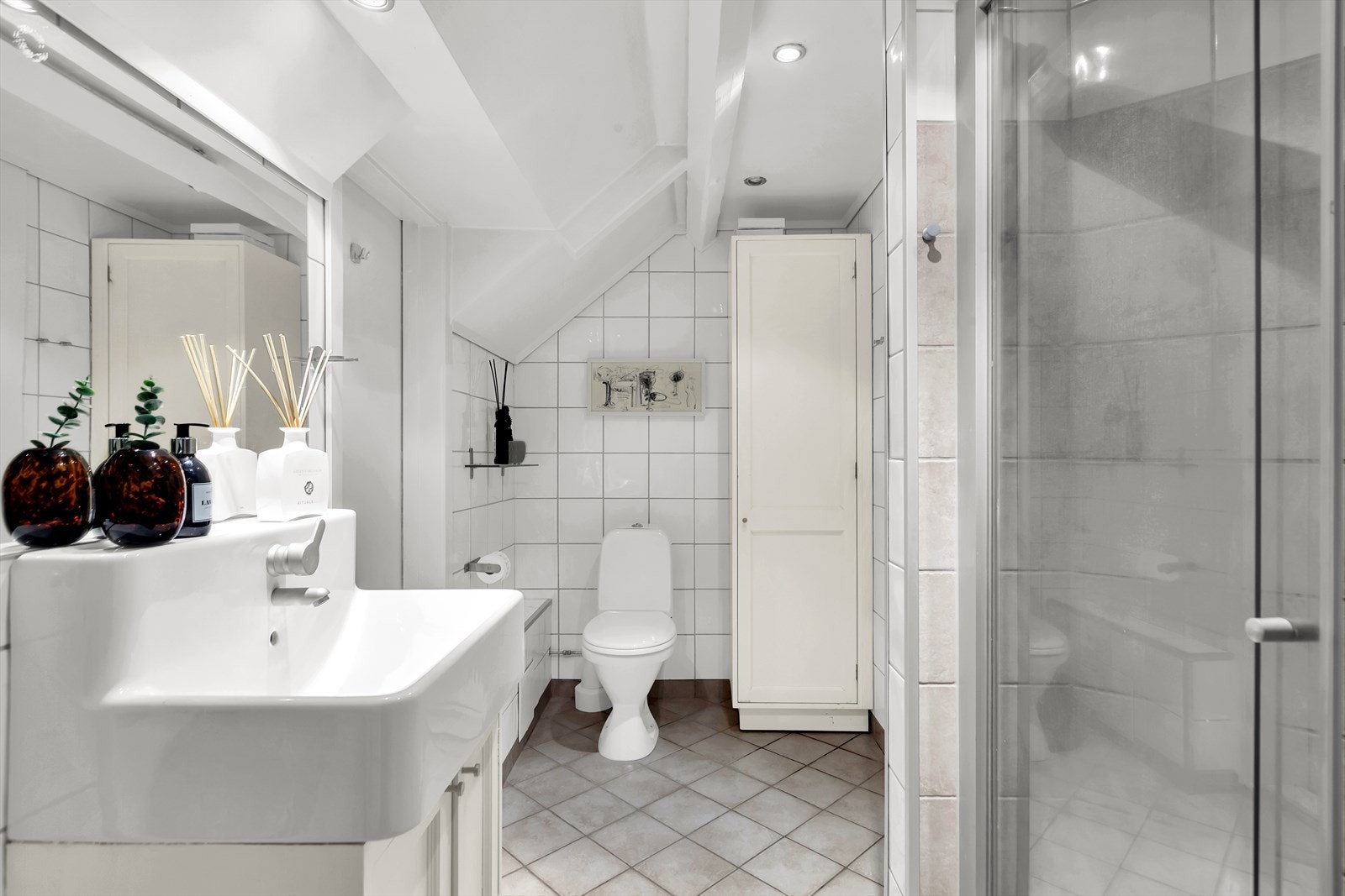 Bad med innredning bestående av nedfelt vask, benk- og høyskap med profilerte fronter. Badet er utstyrt med opplegg for vaskemaskin og varmekabler for ekstra komfort. Galleribilde