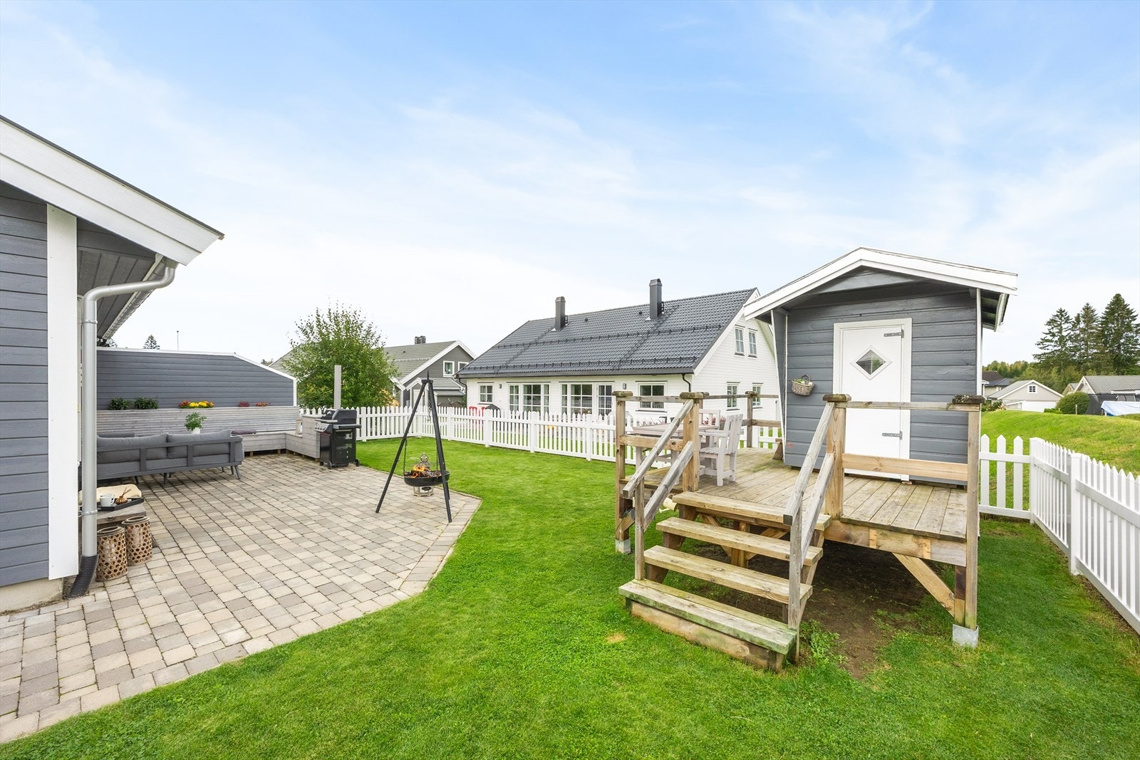Hagen er pent opparbeidet med plen og er rammet inn av et hvitt stakittgjerde. Galleribilde