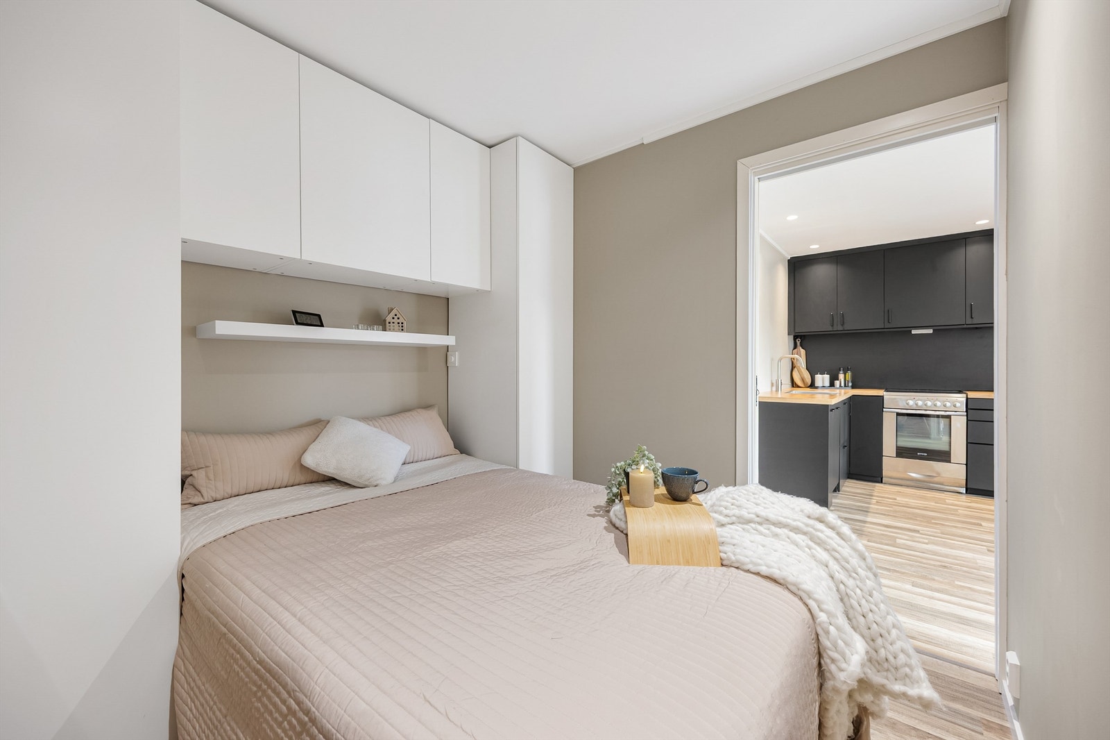Sovealkove med innbydende skap og plass til dobbeltseng. Rommet er malt i en lun, beige tone, og det er døråpning som leder direkte ut til entre og kjøkken. Galleribilde