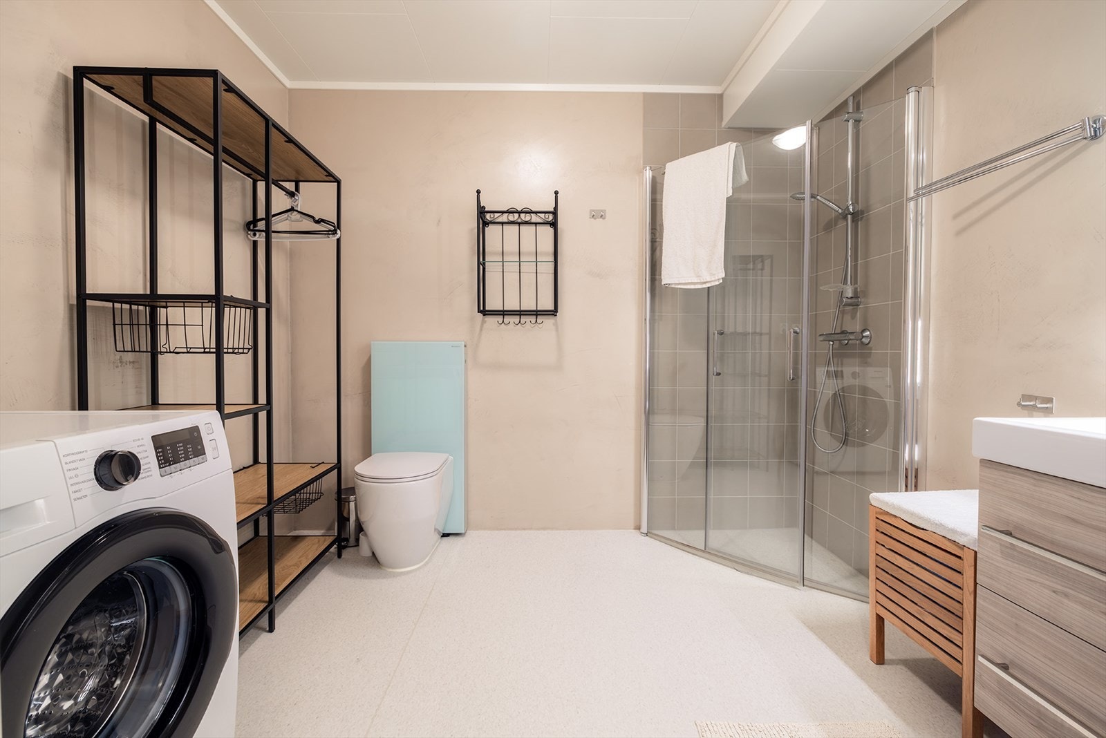 Bad/vaskerom med belegg på gulvet, og plater med microcement overflate på veggene. Galleribilde