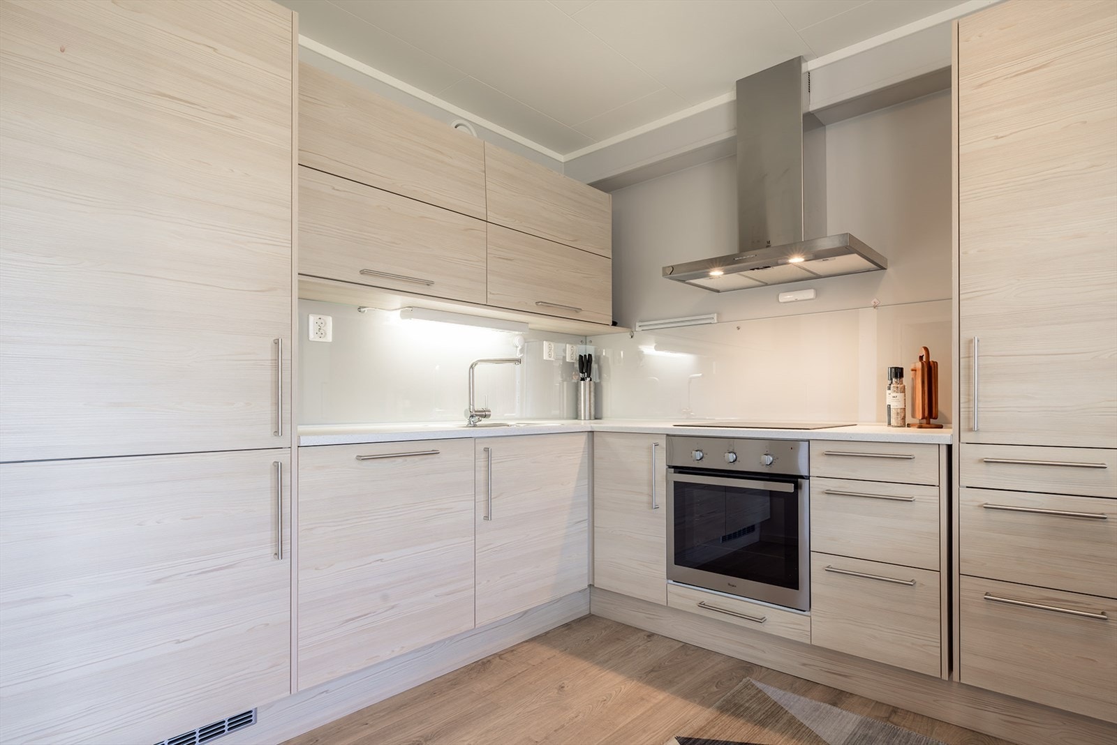 Kjøkkeninnredning med hvite skrog, og folierte fronter. Innredningen er med integrerte hvitevarer med induksjonstopp, steikovn, oppvaskmaskin, kjøleskap, og fryseskap. Galleribilde