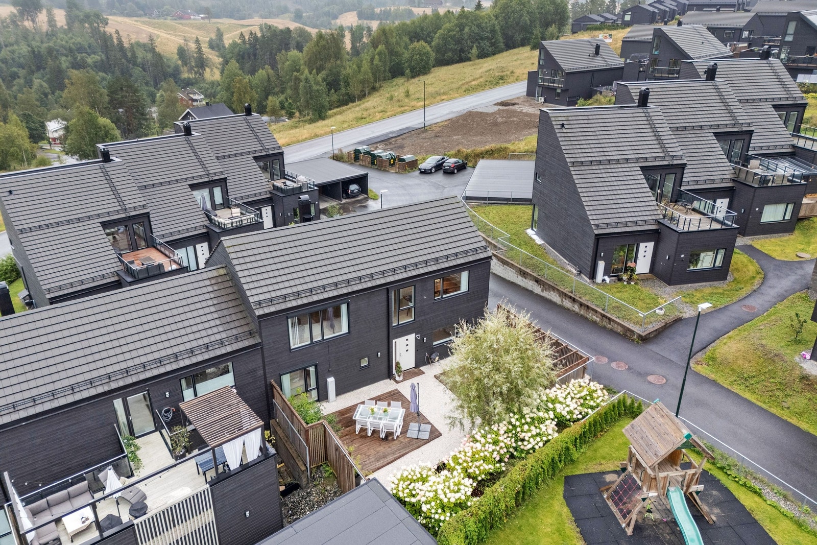 Oversikt over Seterstallen 7 og uteområdet med hvit singel, platting og pergola på forsiden av boligen. Galleribilde