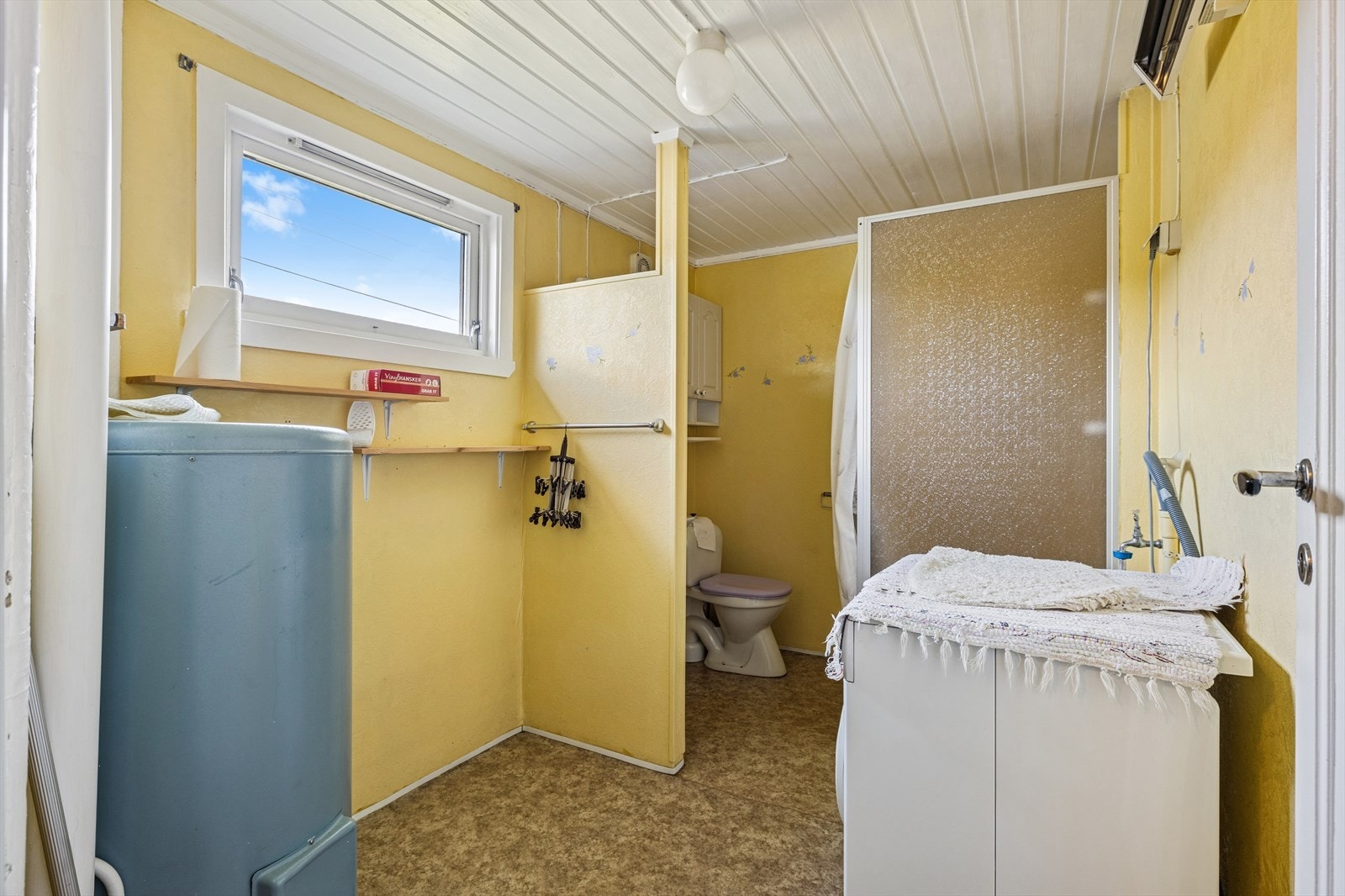 Badet i underetasjen har belegg og noe malt betong på gulv og veggene er med plater og noe mur. Badet er utstyrt med vask, toalett og dusjnisje. Her har man også opplegg for vaskemaskin. Galleribilde