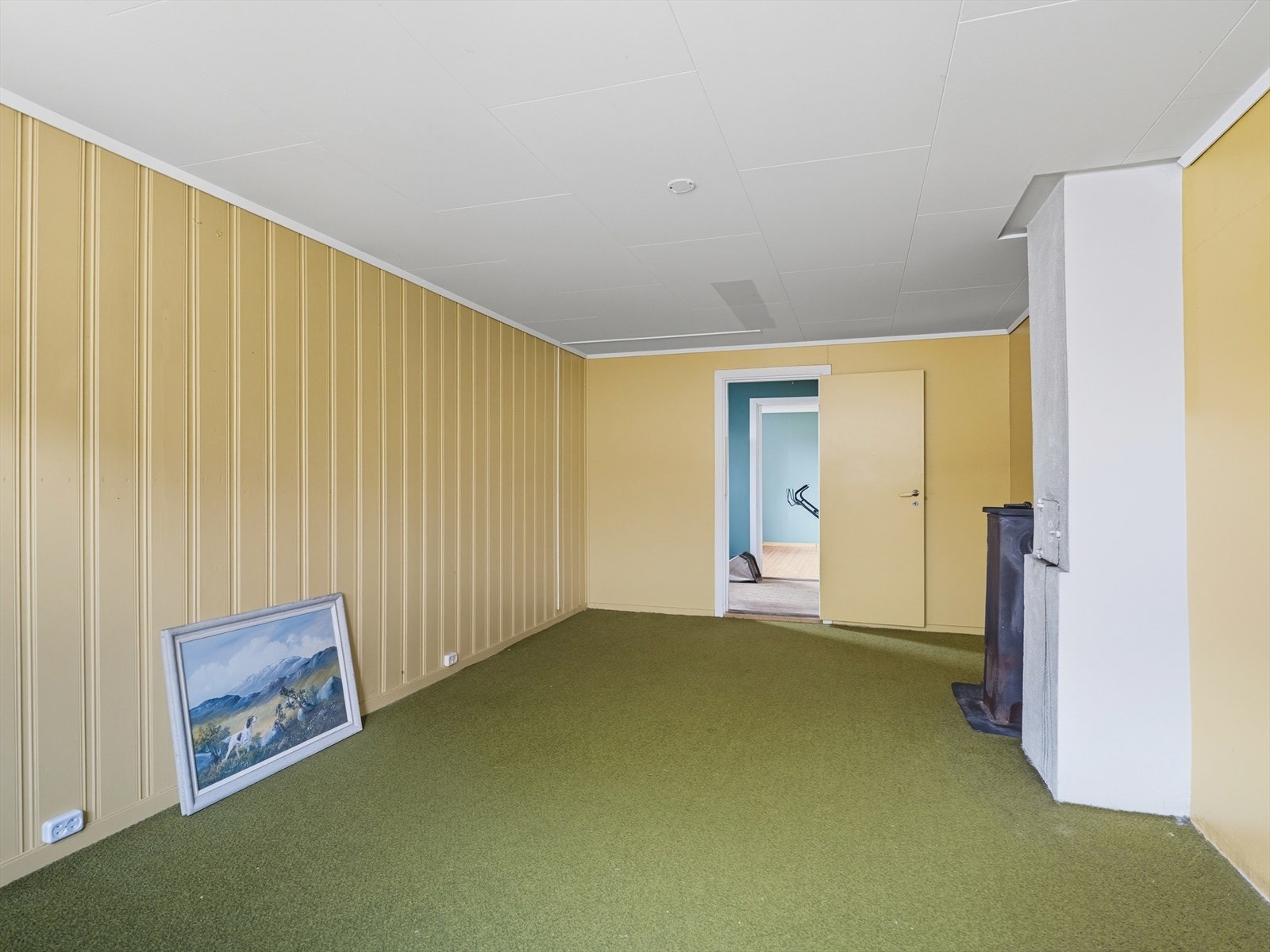 Kjellerstue med teppe på gulv, malt panel og mur på vegg og takess i himling. Galleribilde