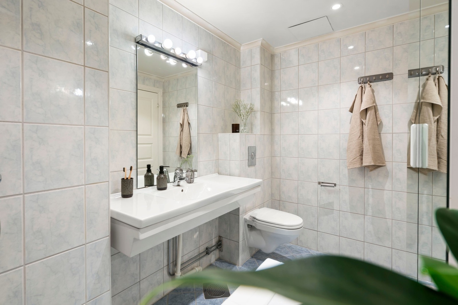 Flislagte vegger og nedforet malt himling med innfelte LED-downlights. Nye downlights i 2024 Galleribilde