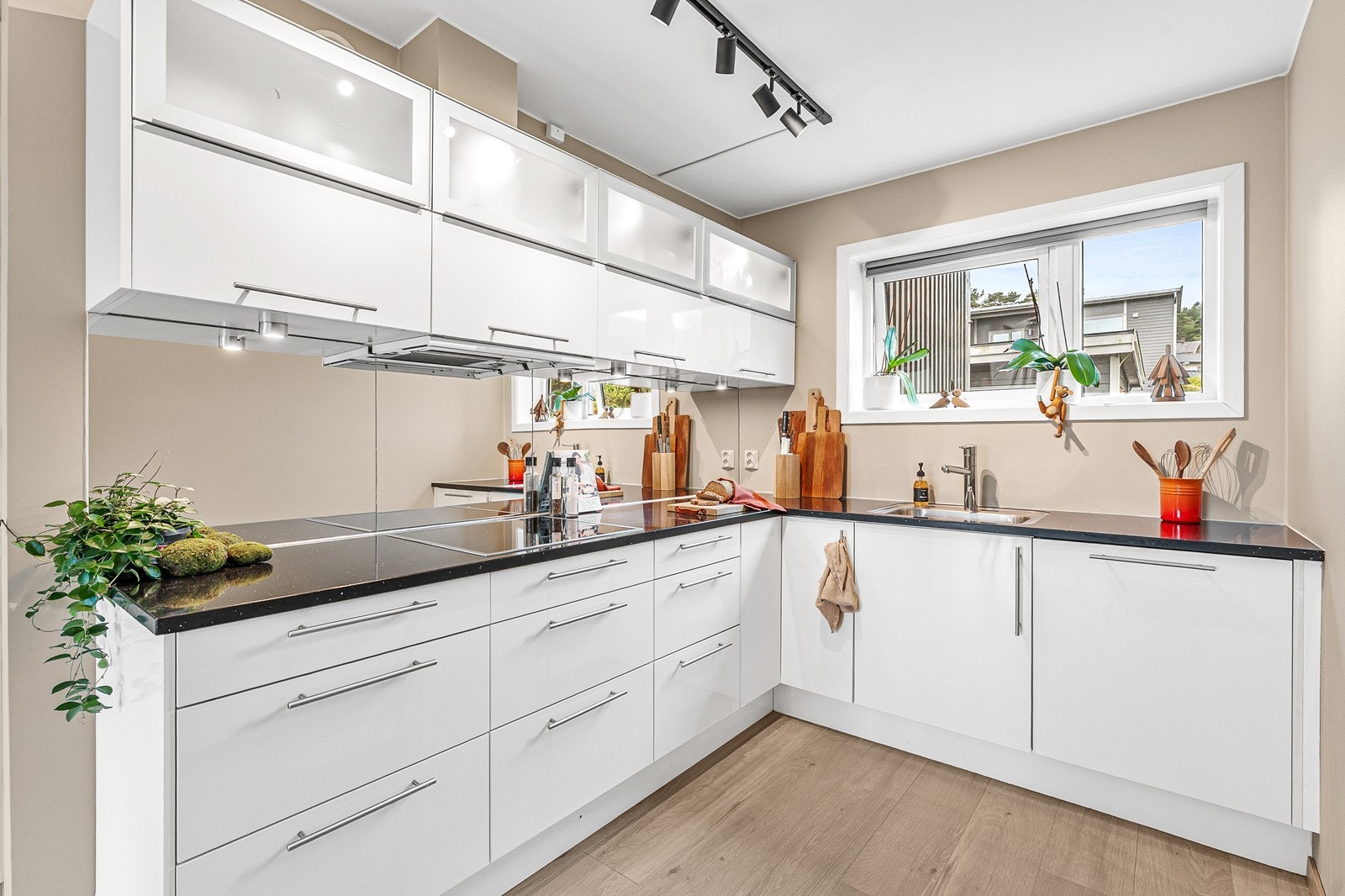 Kjøkkeninnredningen er tidløs, med slette, hvite fronter og en mørk benkeplate som kontrast. Galleribilde