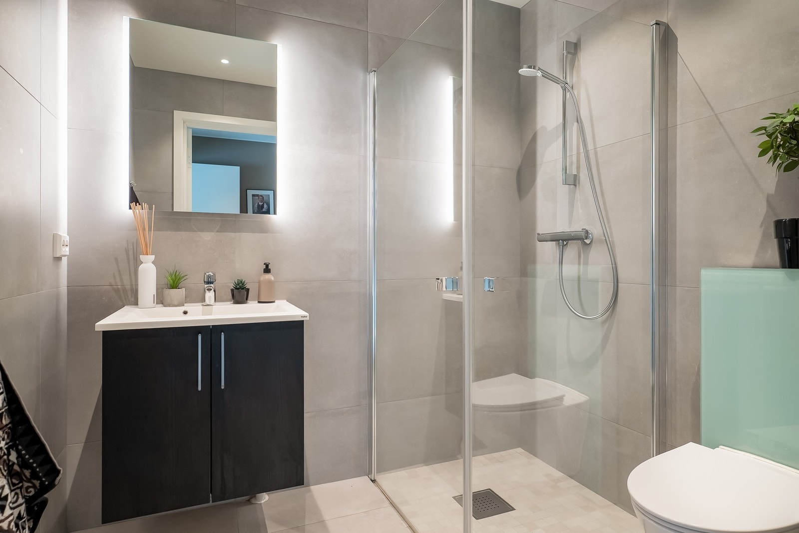 Badet har 60x60 flis på gulv med behagelig gulvvarme. Her er det etablert en praktisk dusj med innfellbare dusjvegger. Downlights i tak. Galleribilde