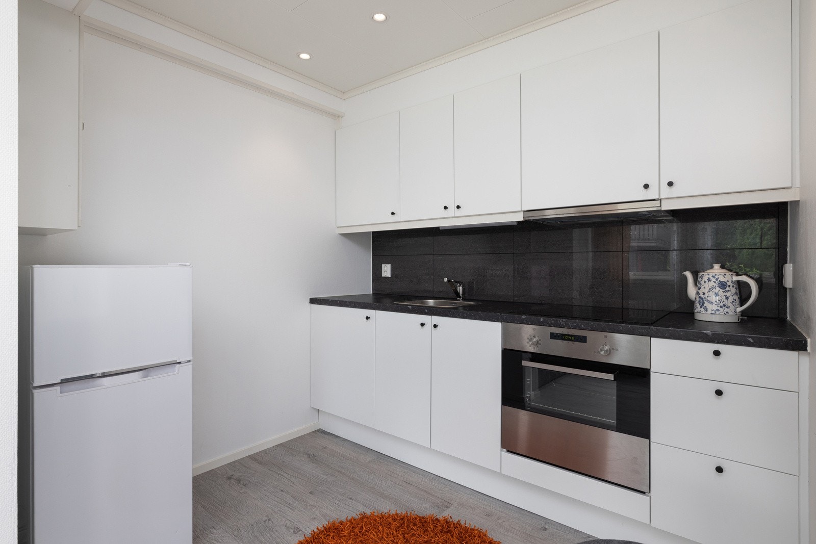 Det er integrert platetopp og stekeovn, samt god plass for frittstående kjøl/fryseskap. Det er fliser i benkerygg som gir en stilren og praktisk utførelse. Galleribilde