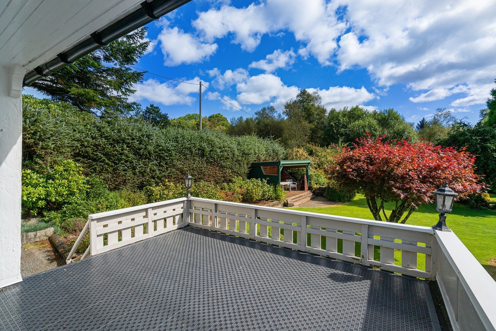 Terrasse med utsyn ut over den store og velpleide hagen Galleribilde