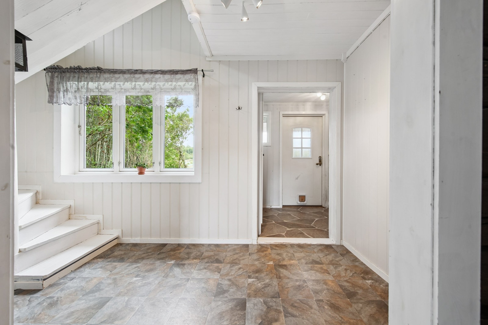 Vi starter i vindfanget, som har en moderne ytterdør med glassfelt og katteluke. Galleribilde