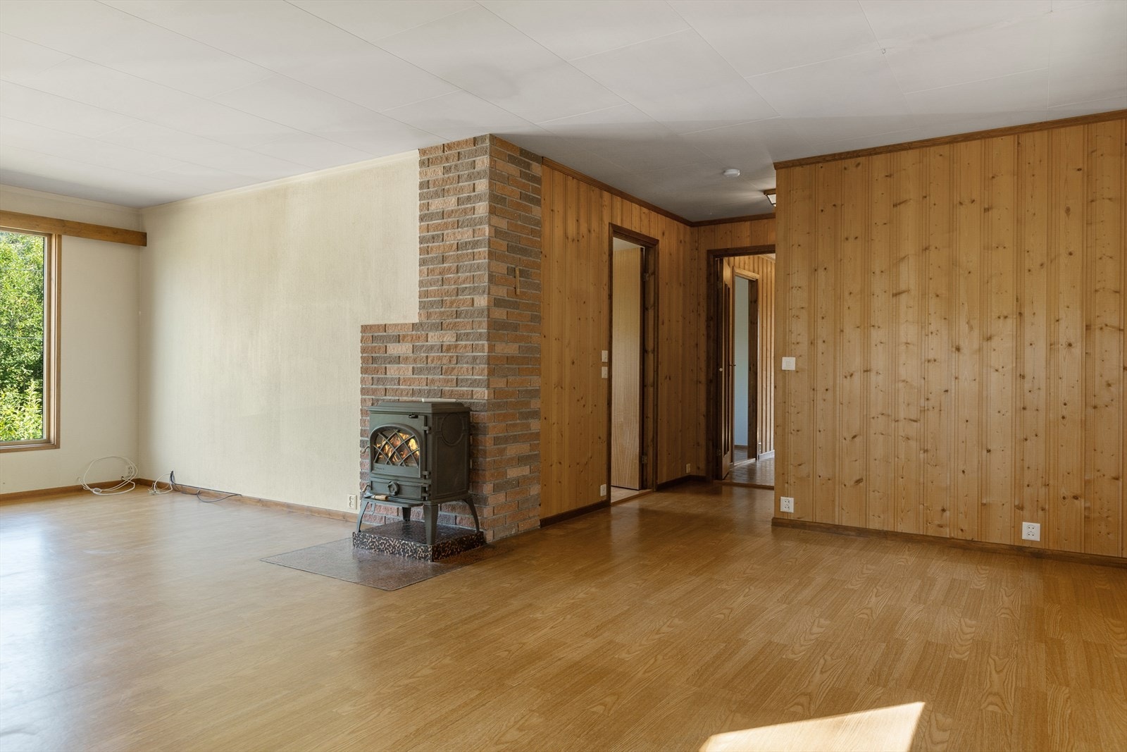 Her er det to store vinduer som slipper inn godt med lys, og en eldre peisovn med innsyn gir lun og god varme til rommet. Galleribilde